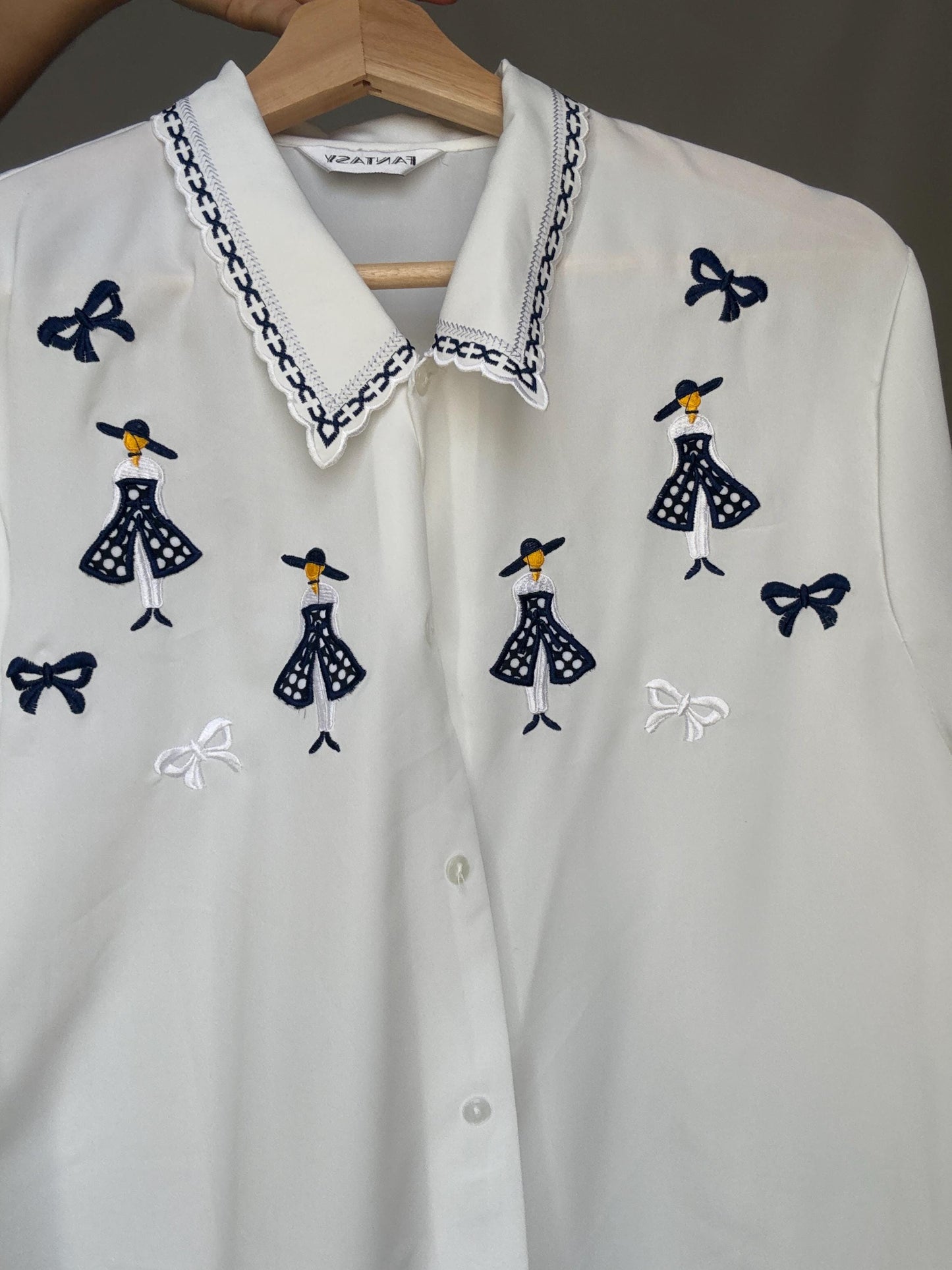 Vintage white embroidered blouse with navy bow and girl motif, shiny lightweight feel – schoolcore cottagecore US L