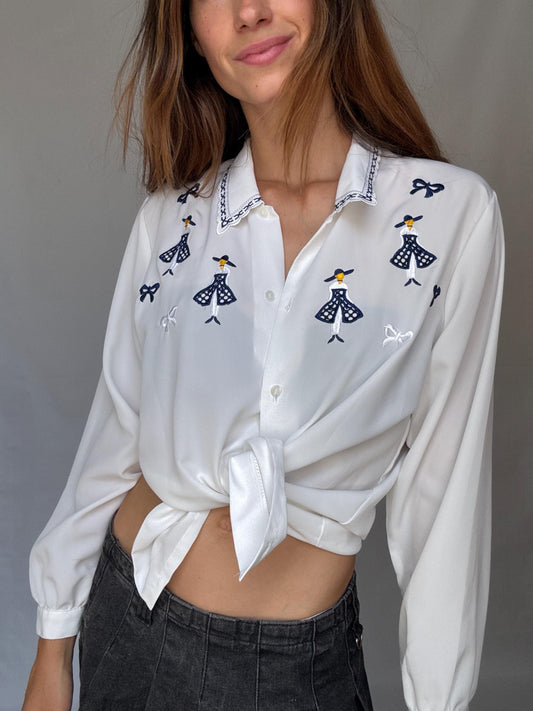 Vintage white embroidered blouse with navy bow and girl motif, shiny lightweight feel – schoolcore cottagecore US L